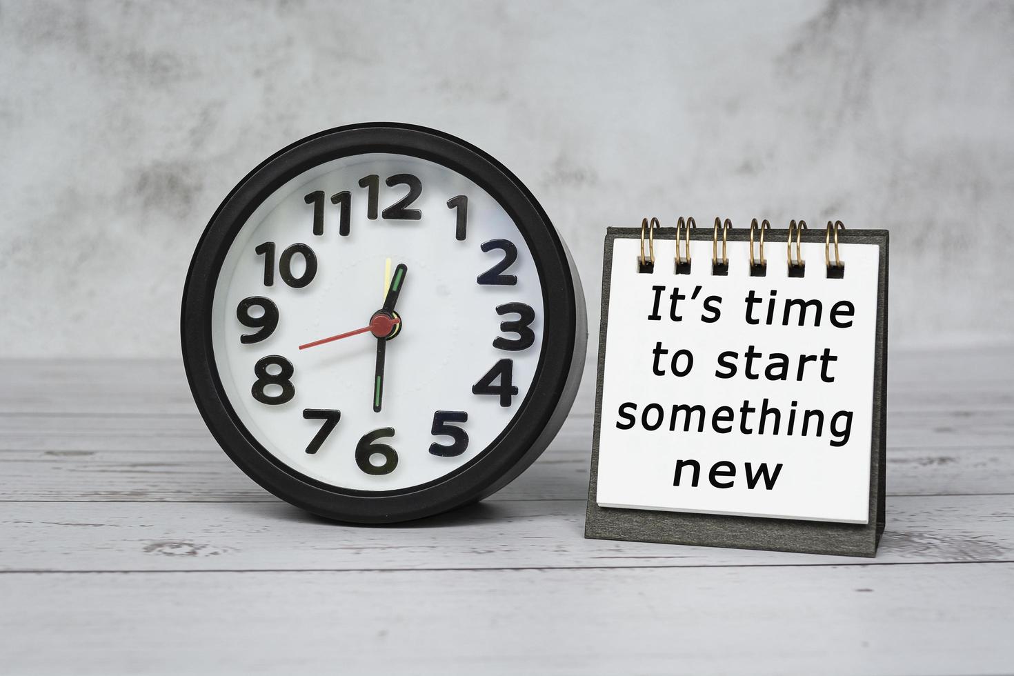 Motivation text on notepad with black alarm clock set time at 12.30 on desk. photo