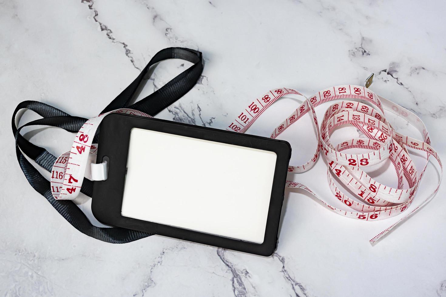 Black name tag with measure tap on white desk. Healthy and diet concept. photo