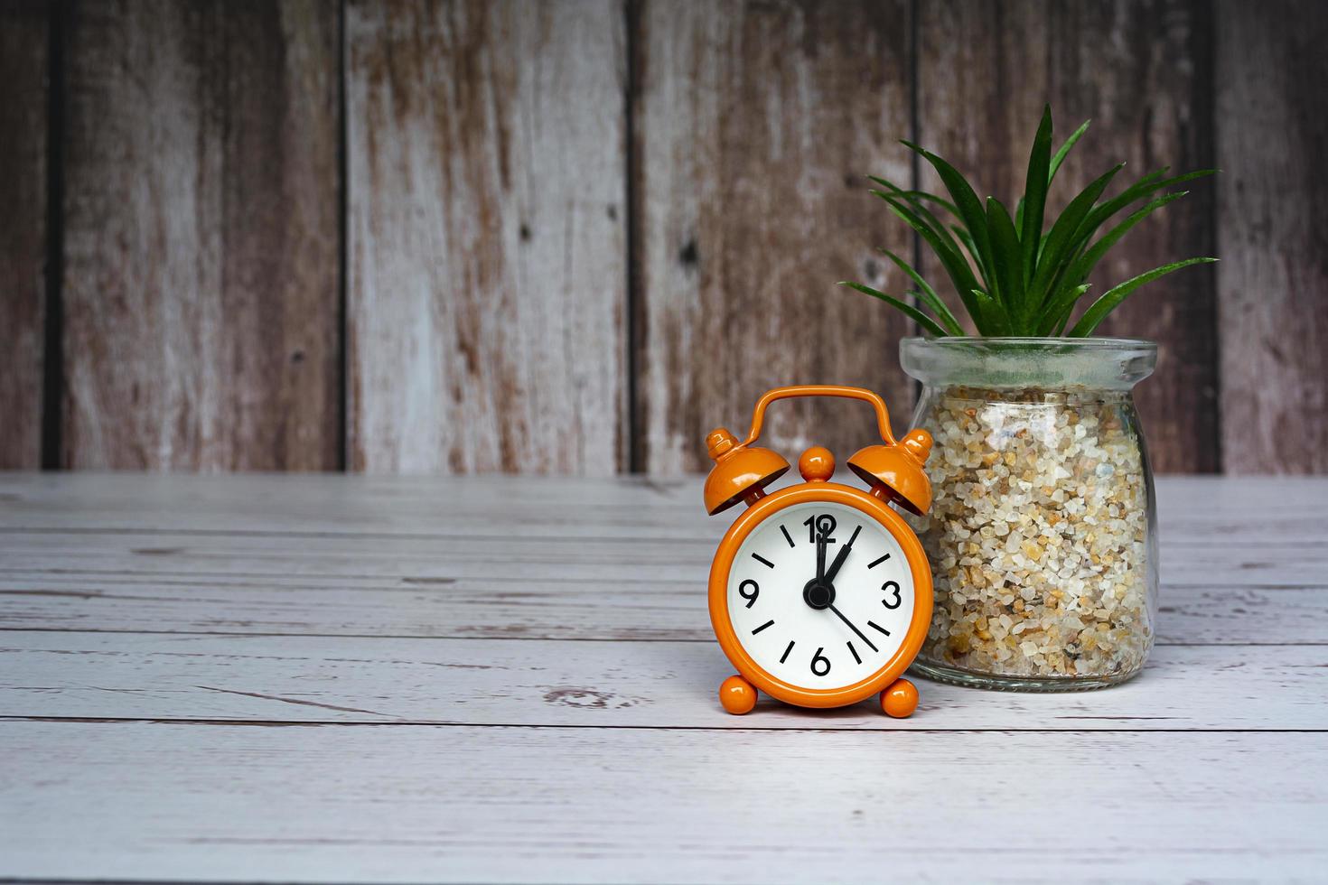 Orange alarm clock isolated on wooden desk. The clock set at 1 o'clock. photo
