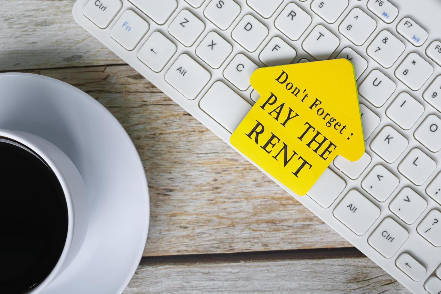 Don't forget, pay the rent text on yellow stick house shape on white keyboard. photo