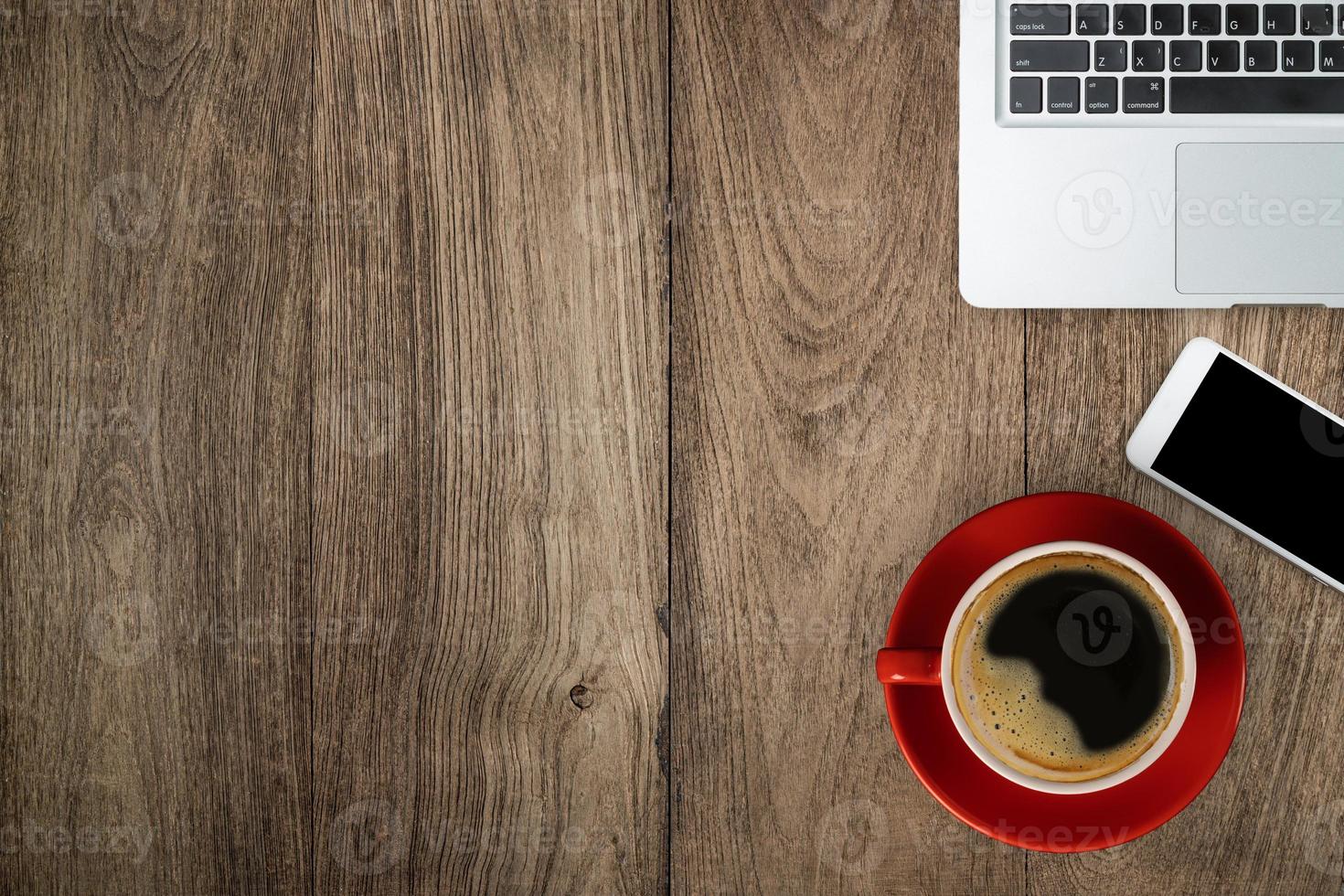 Flay lay red desk with laptop, smartphone and a red cup of black coffee, top view with copy space on wooden table photo