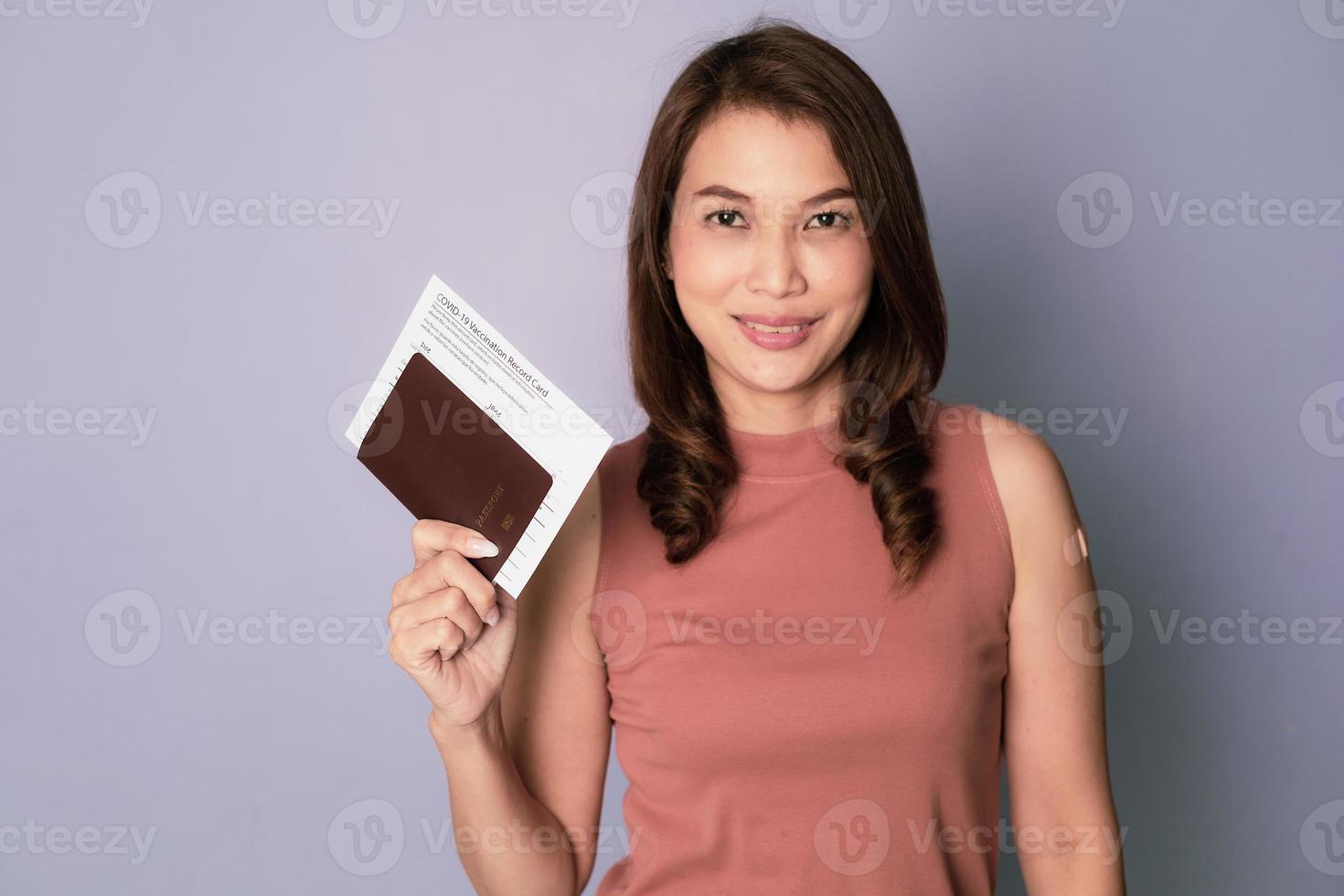Selective focus on passport, Vaccinated Asian woman holding and showing vaccine injection record card and passport in concept of ready to travel after Covid-19 vaccination and finish virus outbreak photo