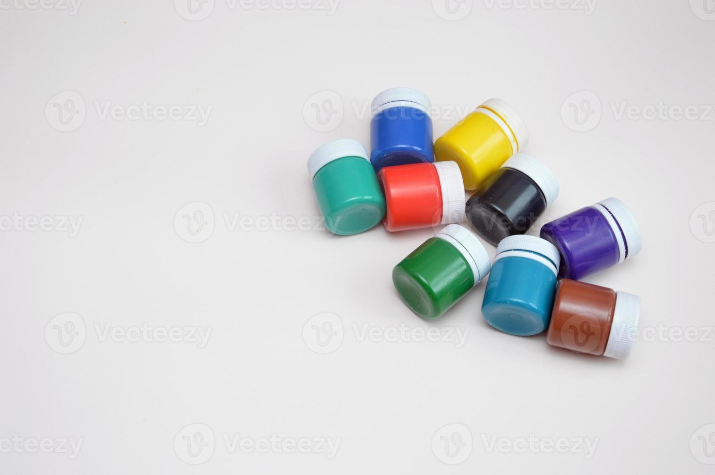 Closed jars with gouache of different colors on a light background. Creativity, hobby. photo