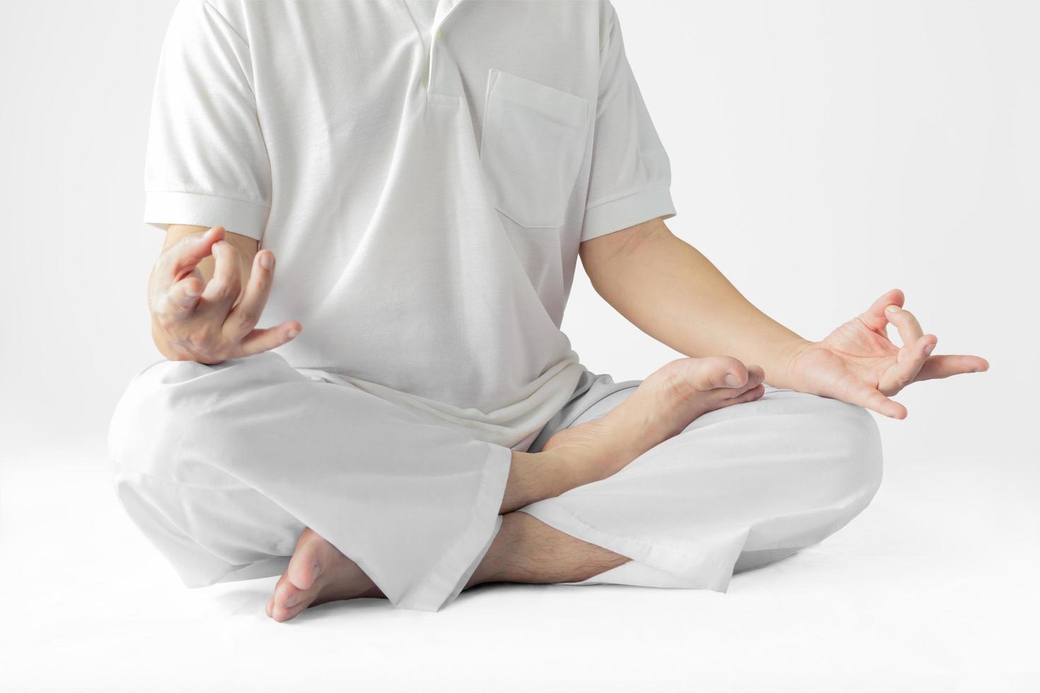 un hombre con una túnica blanca meditando sobre un fondo blanco con un sendero recortado. foto