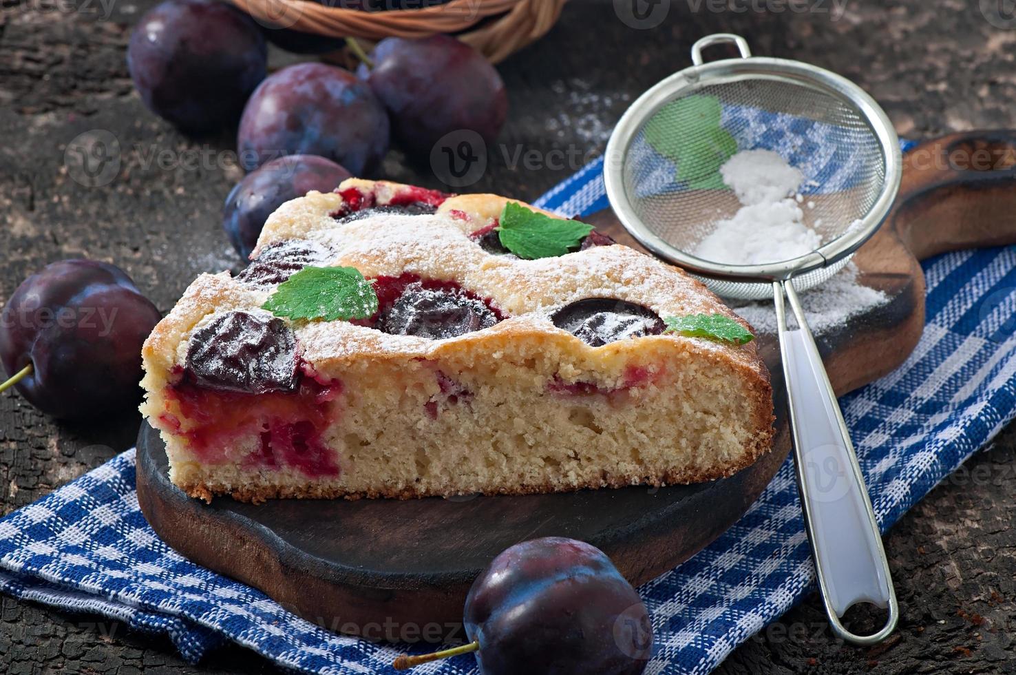 Delicious homemade cake with plums on a wooden background photo