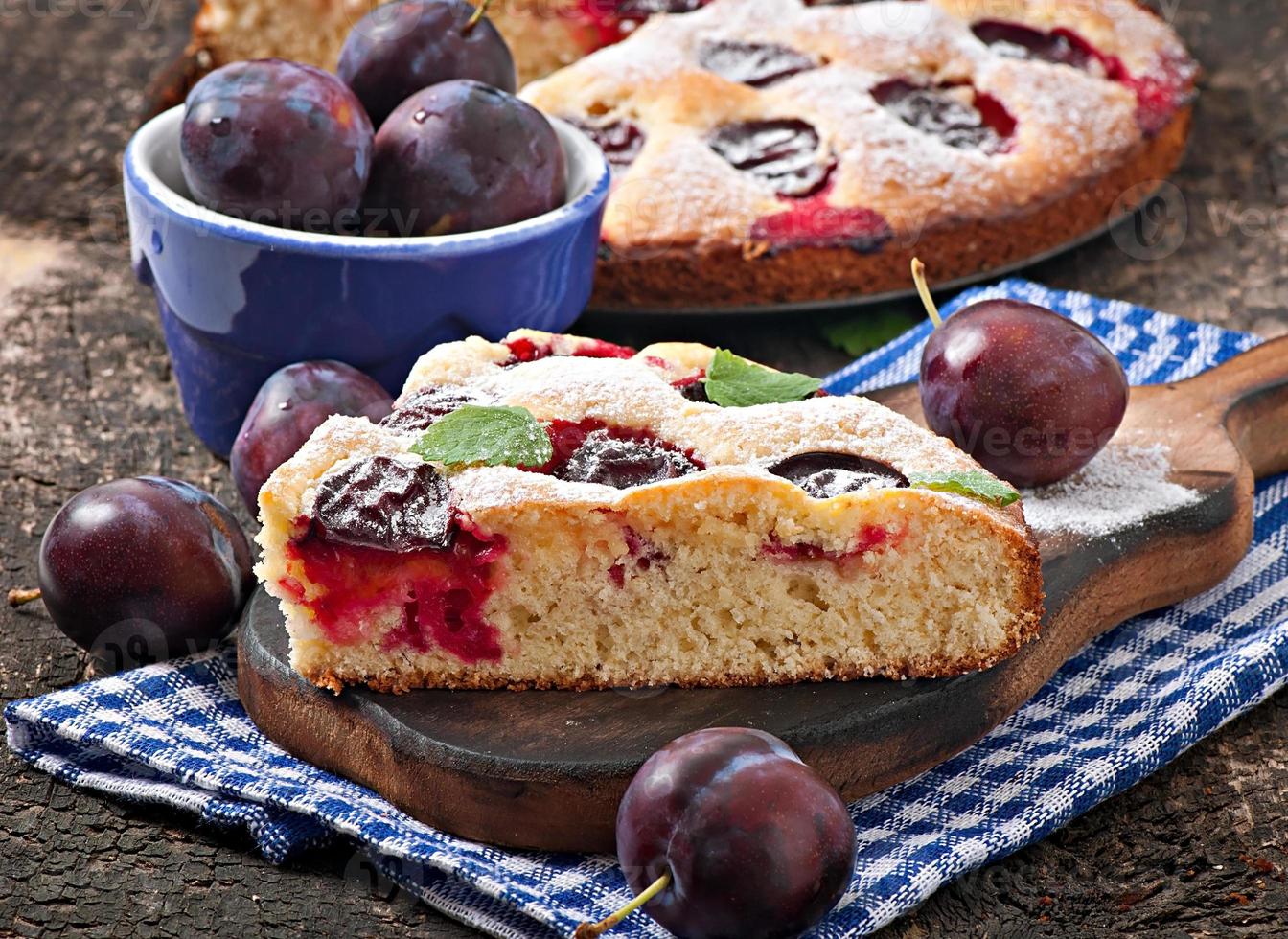 Delicious homemade cake with plums on a wooden background photo