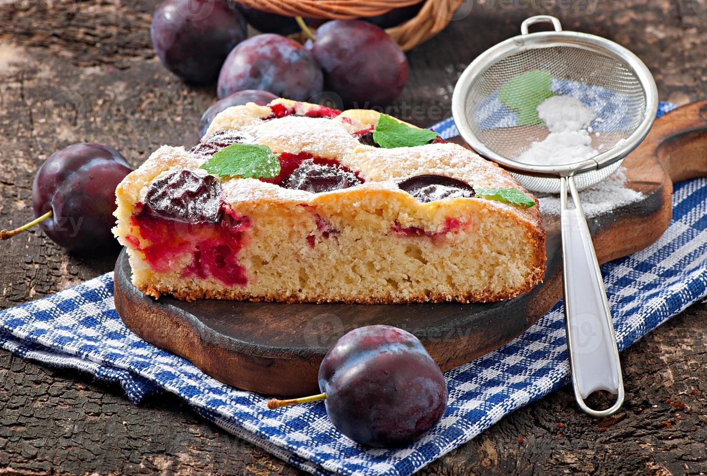 Delicious homemade cake with plums on a wooden background photo