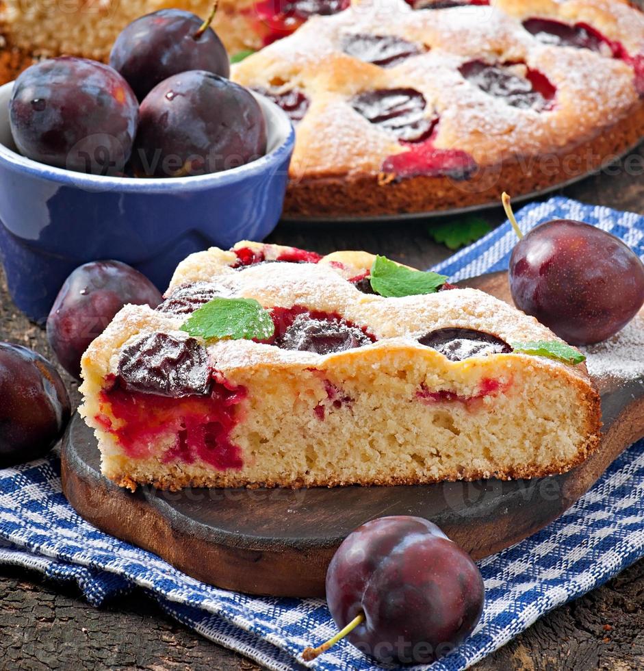 Delicious homemade cake with plums on a wooden background photo