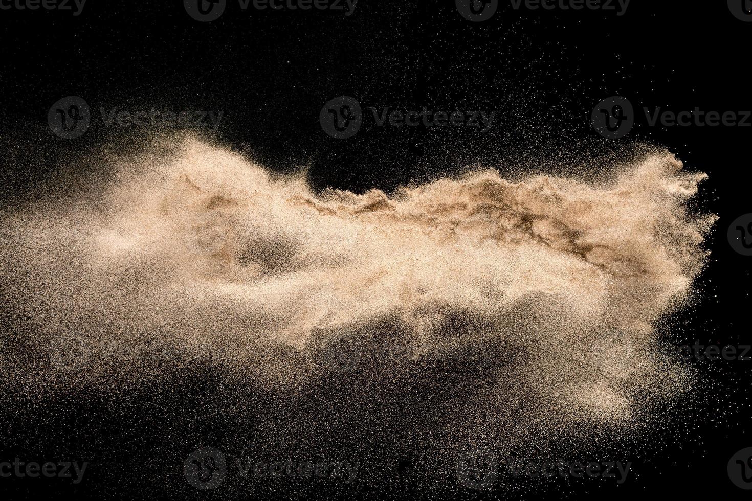 Dry river sand explosion. Golden colored sand splash agianst dark background. photo