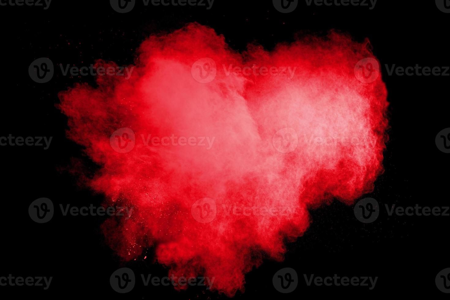 Red heart color powder explosion on black background.Freeze motion of red dust particle splashing. photo