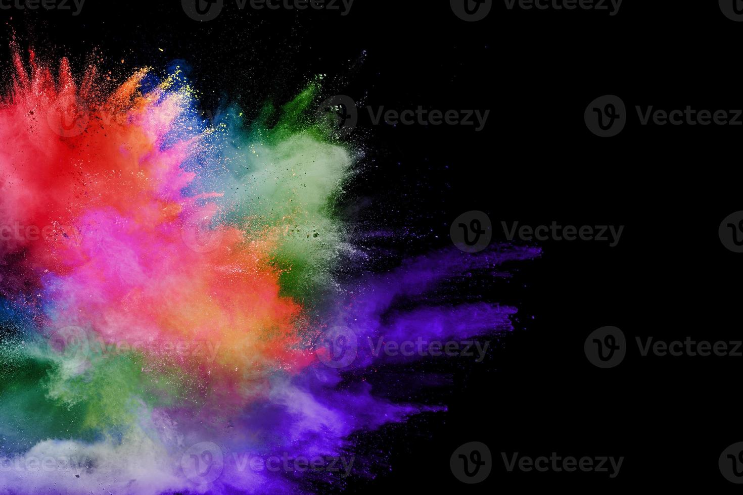 Abstract multicolored powder explosion on black background. Color dust particle splattered on background. photo
