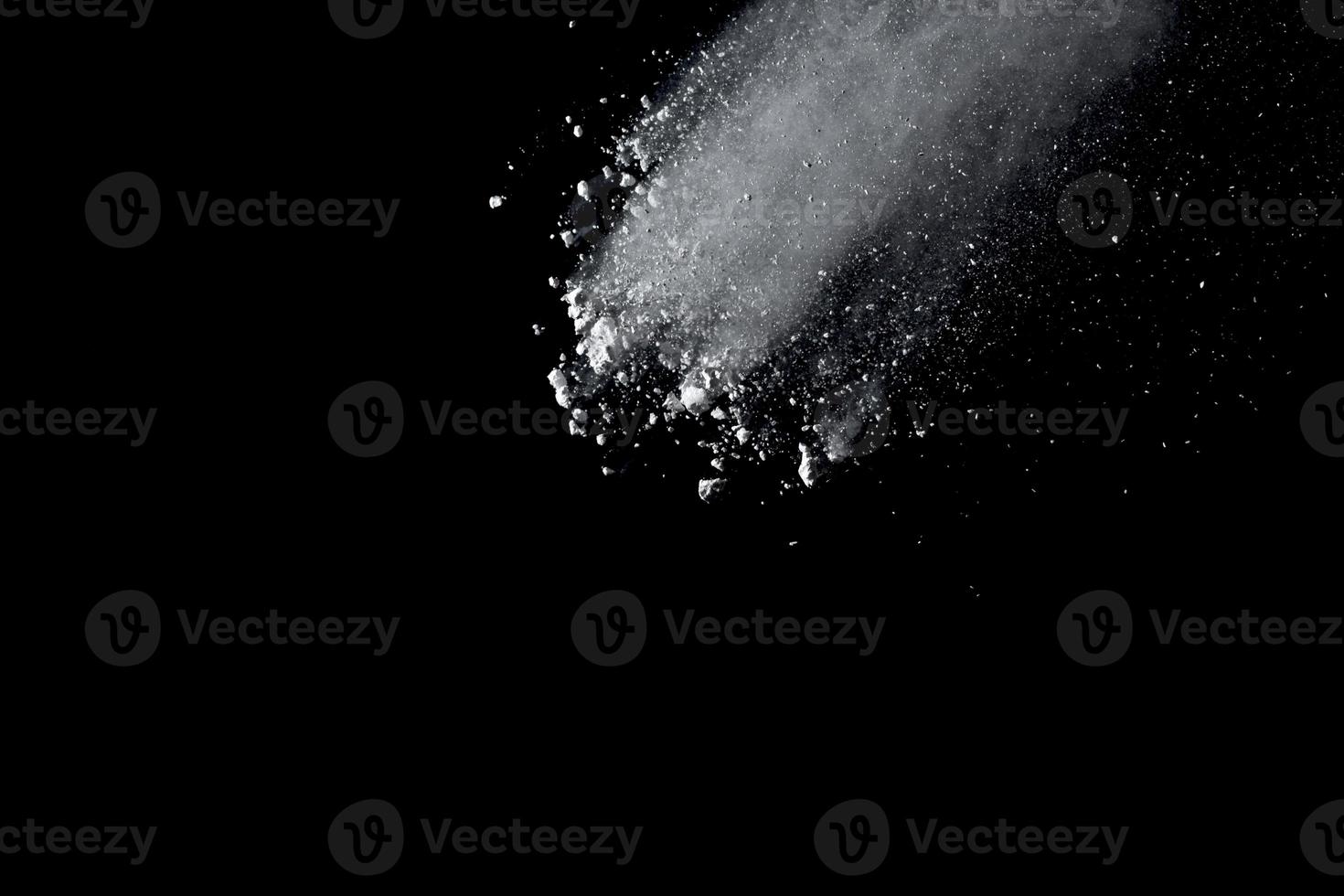 White powder explosion isolated on black background.White dust particle splash. photo