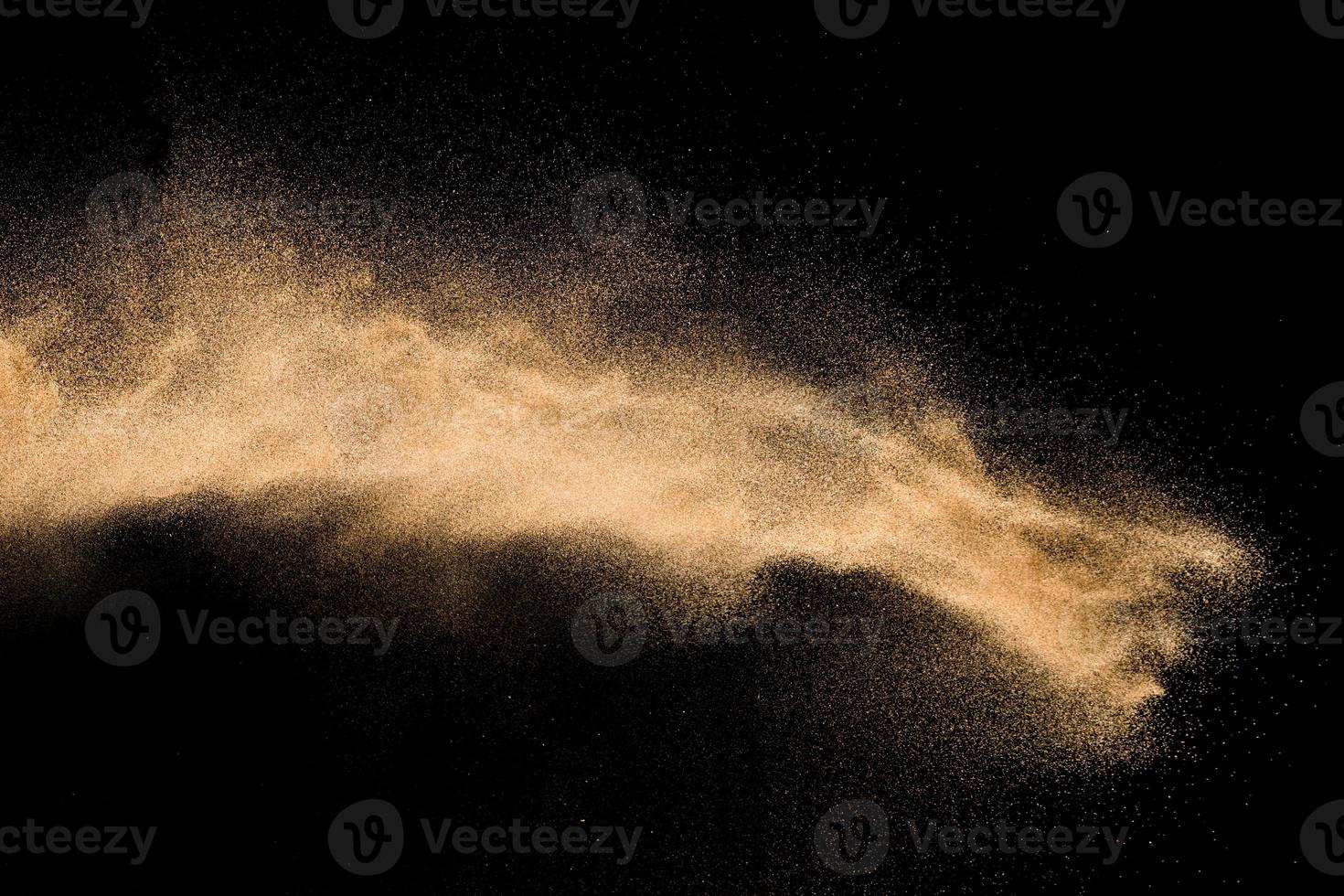 Dry river sand explosion. Golden colored sand splash agianst dark background. photo