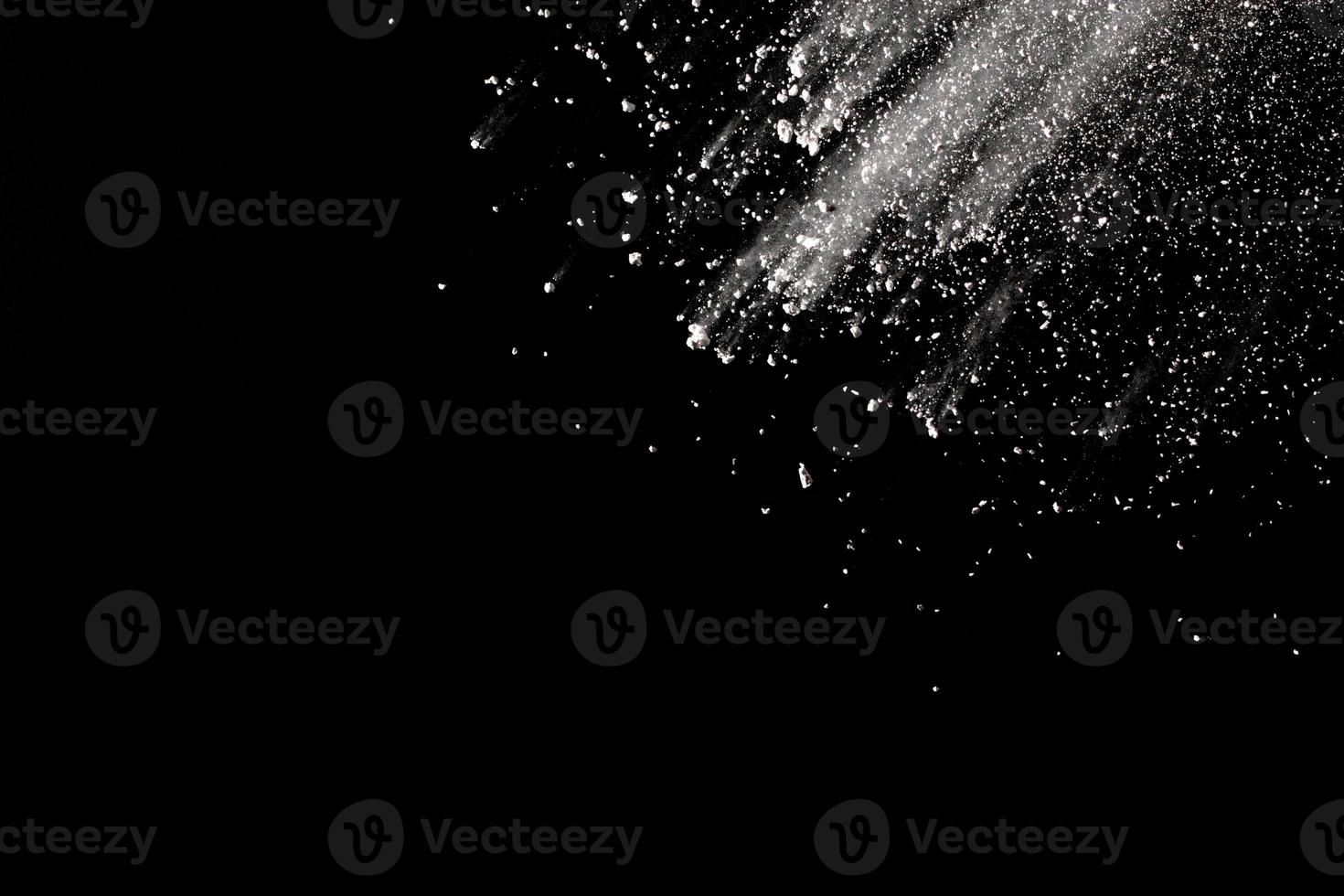 White powder explosion isolated on black background.White dust particle splash. photo