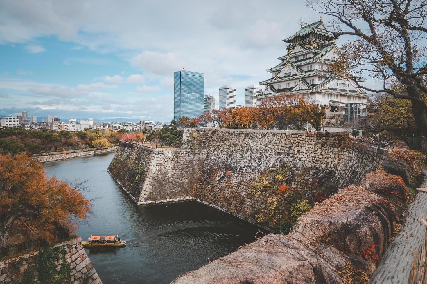 Osaka castle surrounded by the stones sheer walls with modern building and blue sky background in autumn season, Osaka City, Kansai, Japan. Castle is one of Japan's most famous landmarks. photo