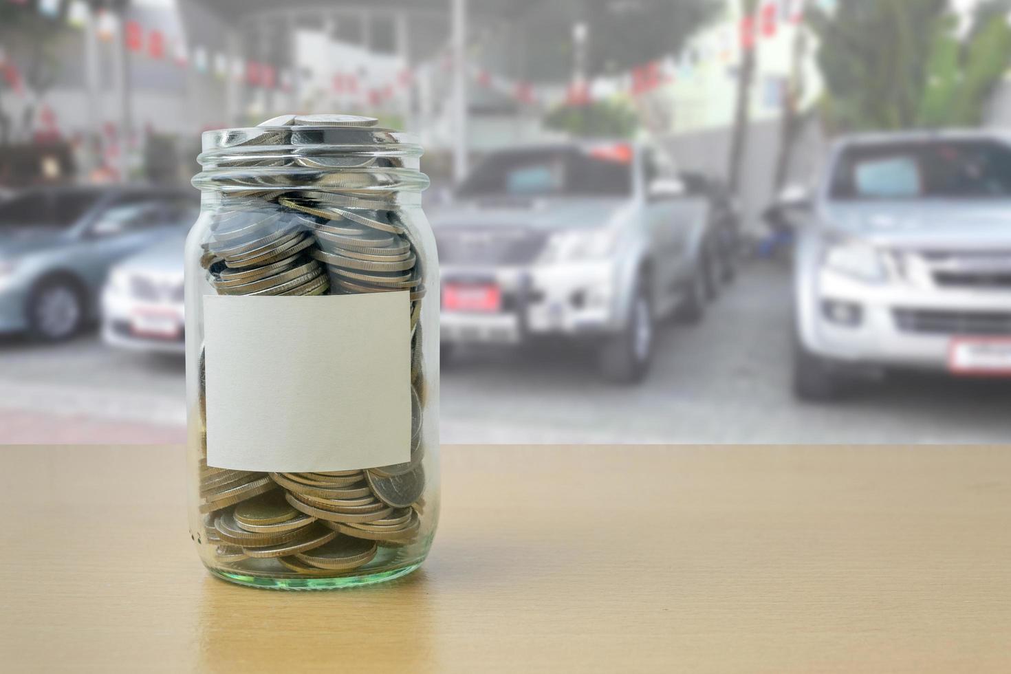 dinero en la botella de vidrio con desenfoque de fondo de la sala de exposición de automóviles foto