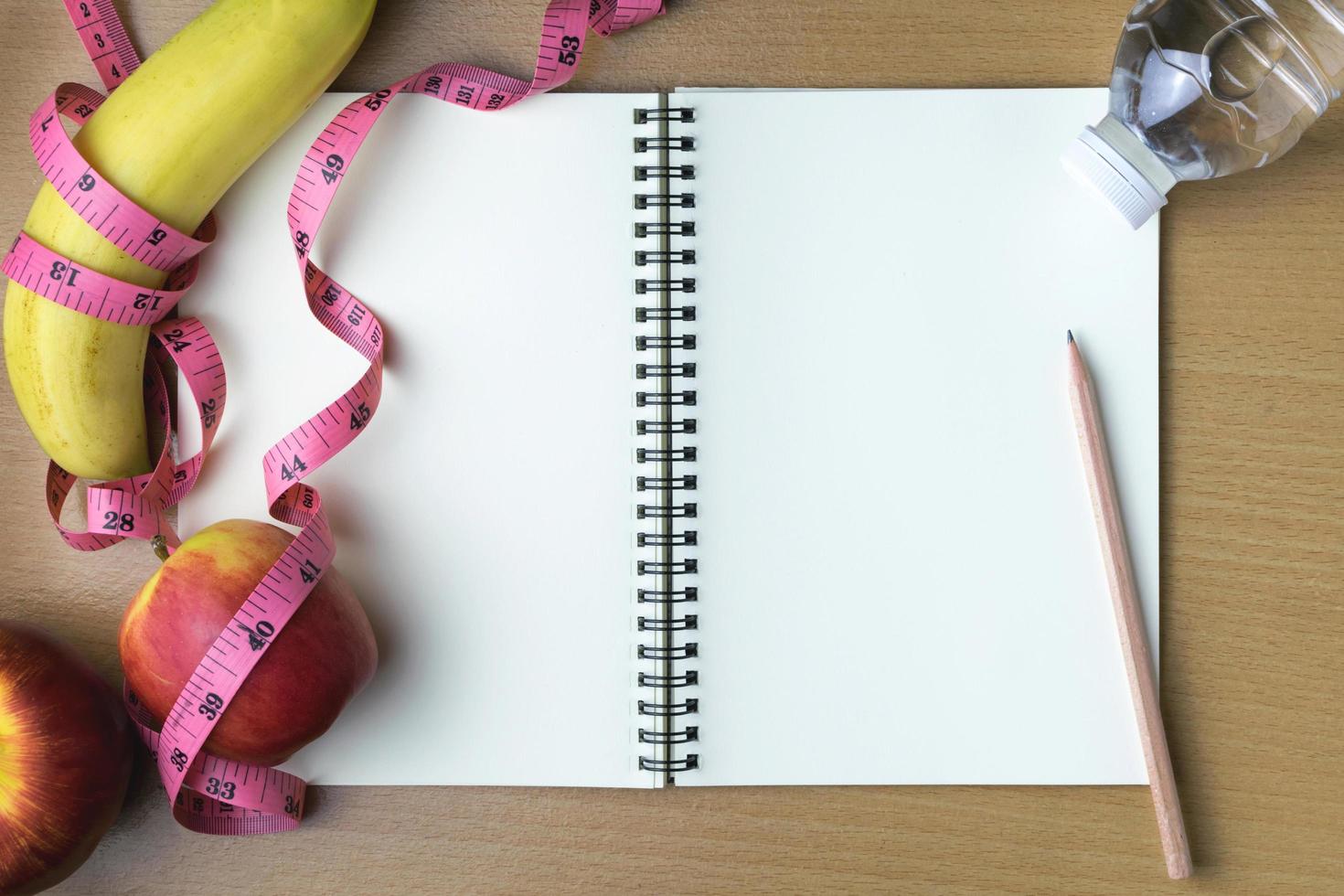 Healthy eating concept, tape measure, fruit and water bottle on a wooden background, blank copy space notebook photo