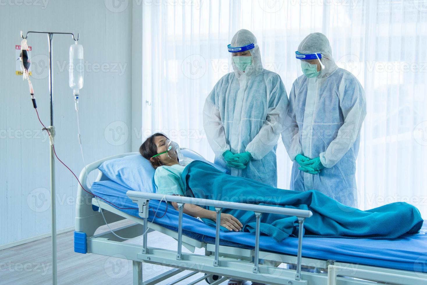 Aging woman patient infected with CORONA VISRUS or COVID-19 and two medical staffs is standing beside patient bed in ICU and quarantine room at the hospital. photo