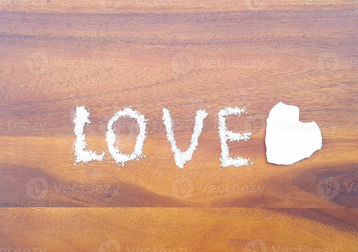 Love or Valentine concept. Closed up tear paper in heart shape and salt in love message on isolated wooden surface background photo