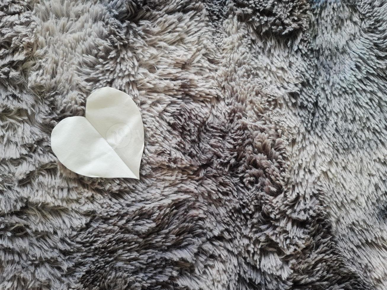 Love or Valentine concept. White tissue in heart shape on grey carpet surface background photo