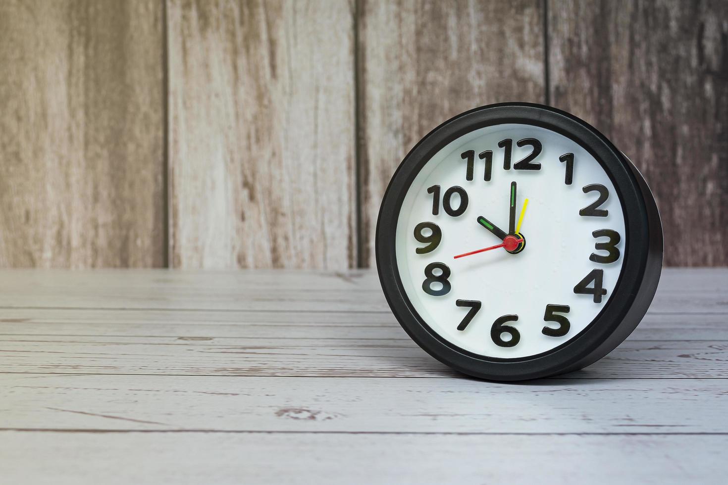 Black alarm clock isolated on wooden desk. The clock set at 10 o'clock. photo