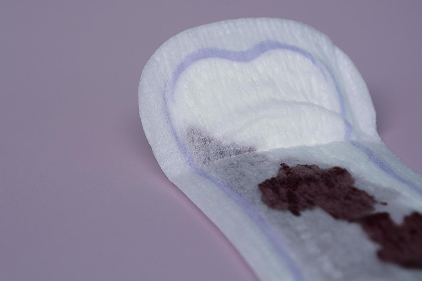 Menstrual blood on a sanitary pad on pink background. Flat lay photo