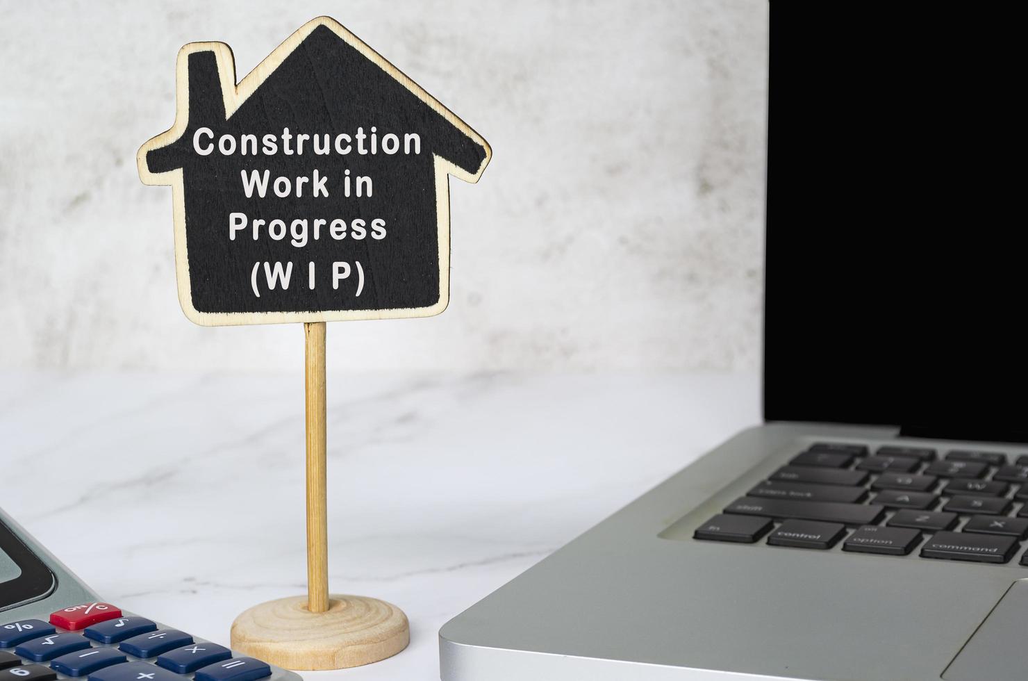 Construction Work in Progress text on wooden house model with on white table. photo