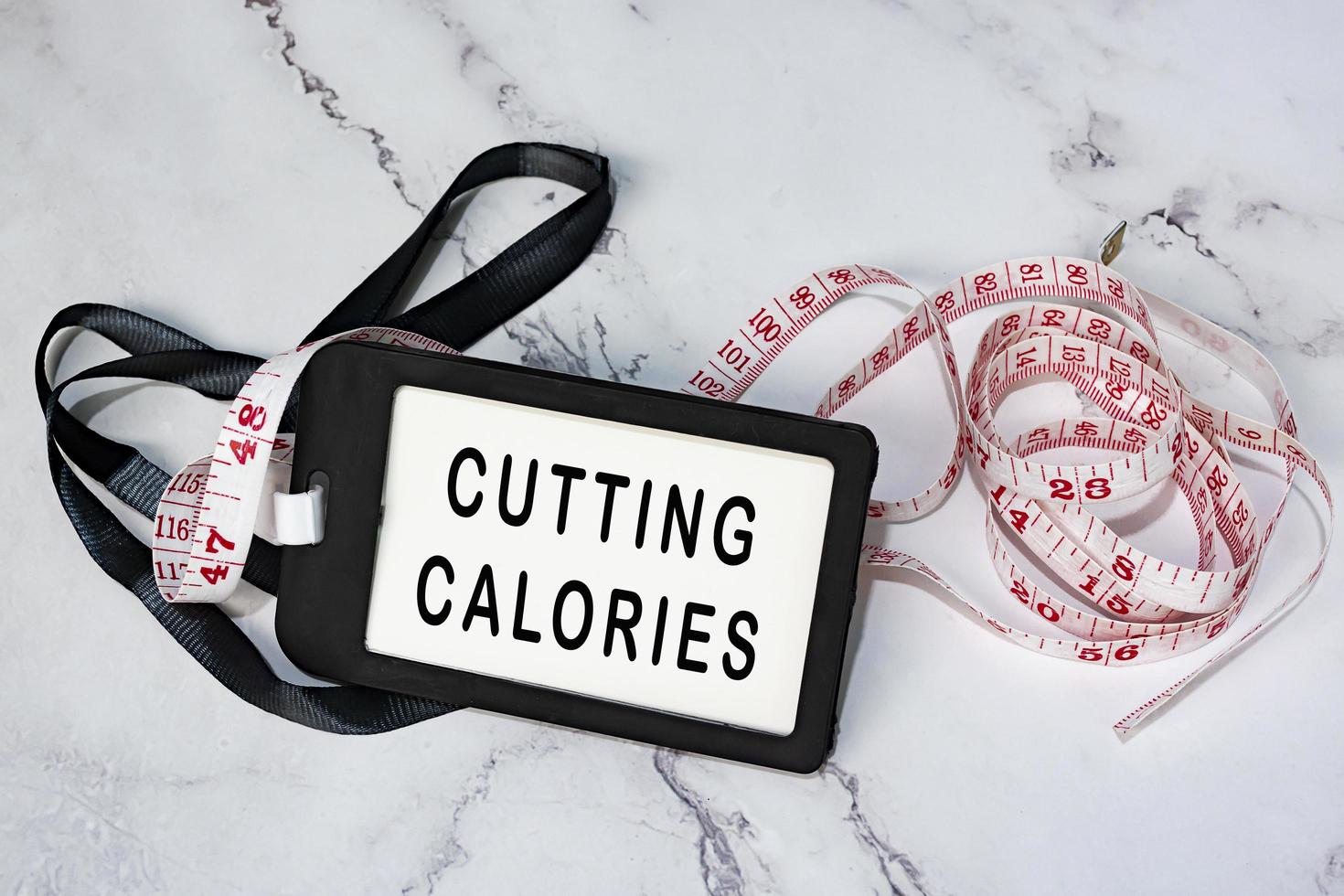 Cutting calories on black name tag with measure tap on white desk. photo