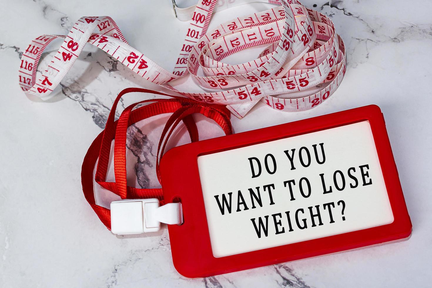 Do you want to lose weight text on a red name tag with measure tap on white desk photo