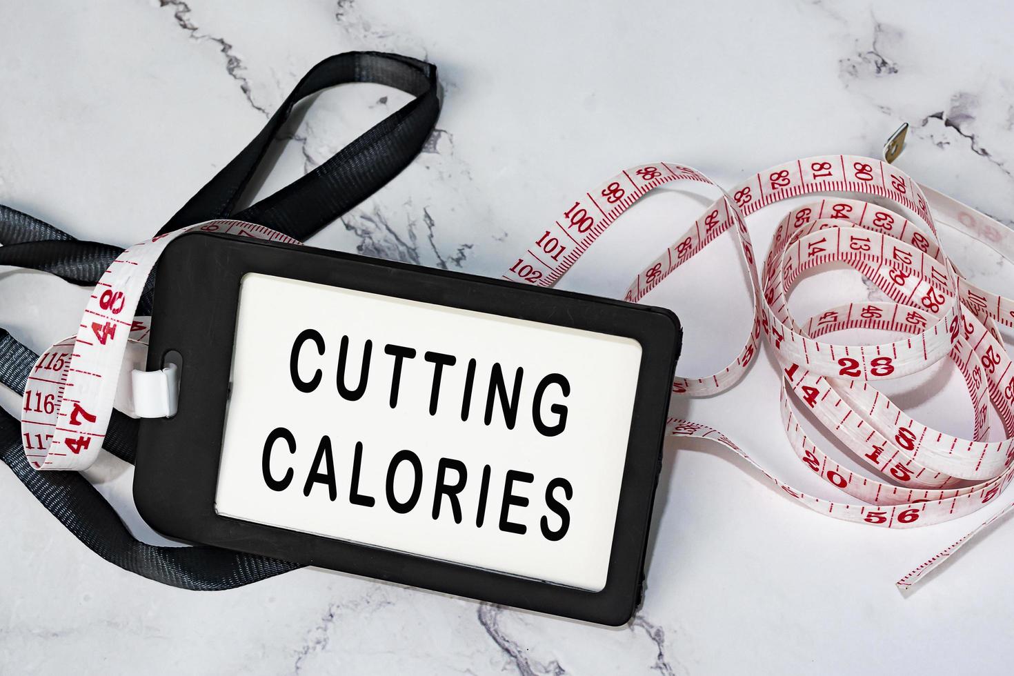 Cutting calories on black name tag with measure tap on white desk. photo