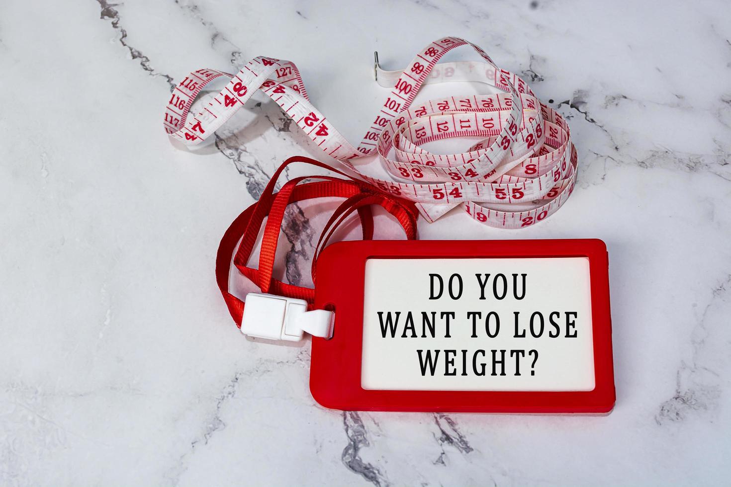 Do you want to lose weight text on a red name tag with measure tap on white desk photo