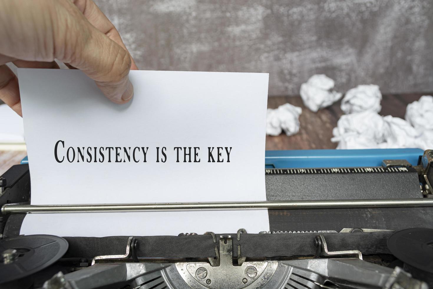 Hand pulling a piece of white paper with quote from an old classic typewriter. photo