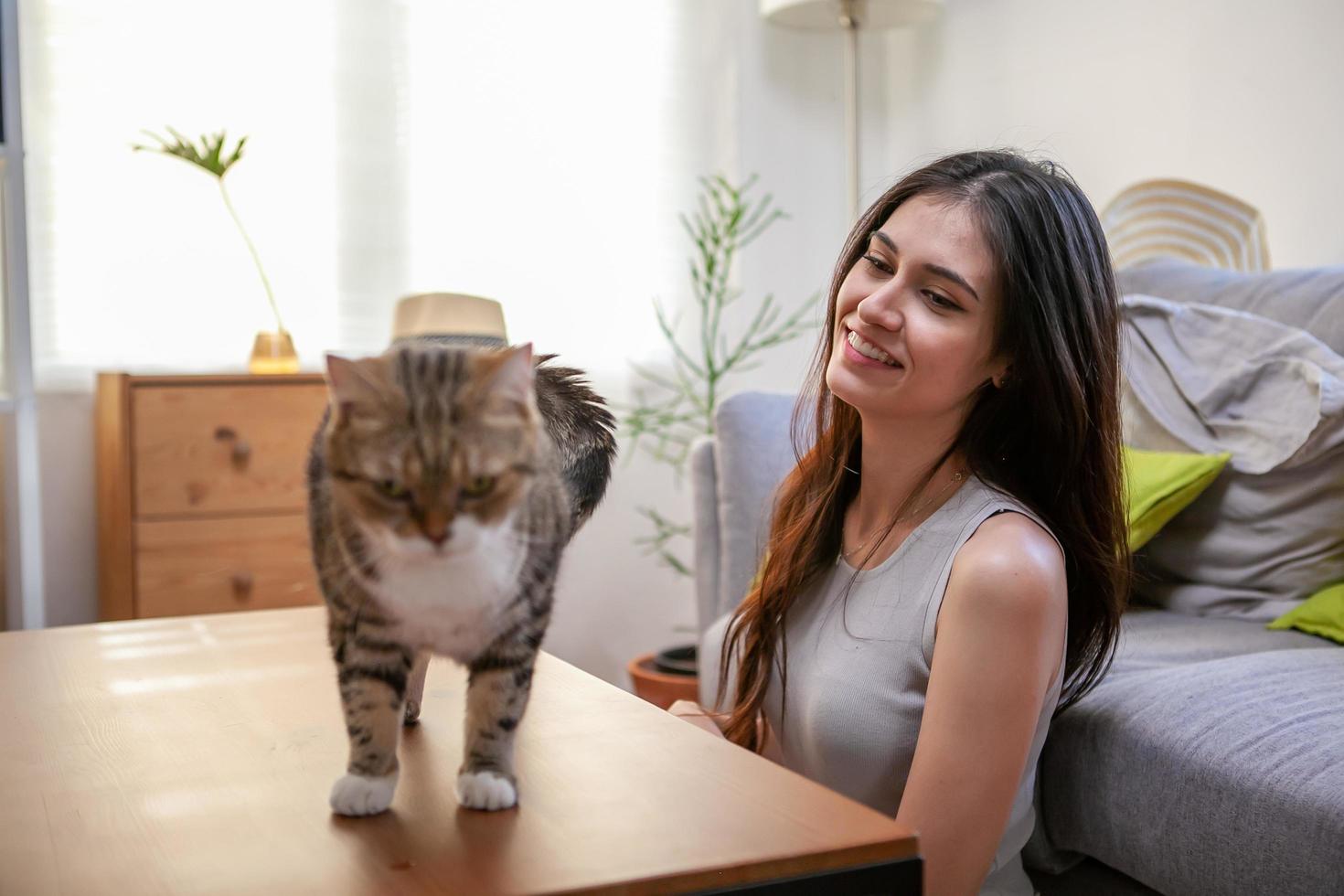 mujer joven jugando con gato en el suelo en casa. foto