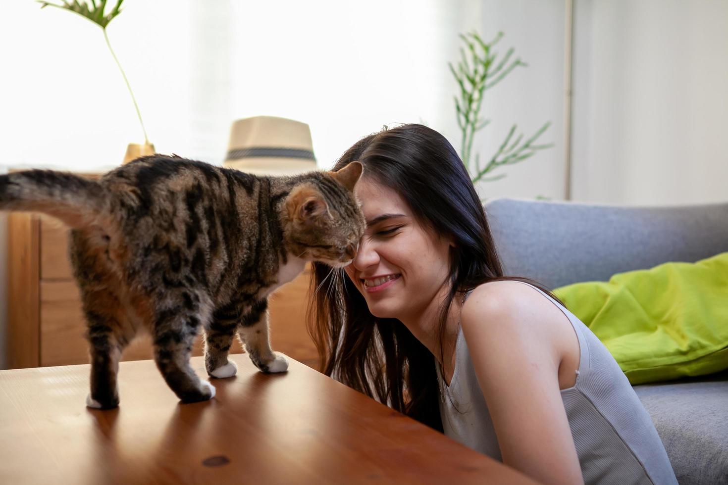 mujer joven jugando con gato en el suelo en casa. foto