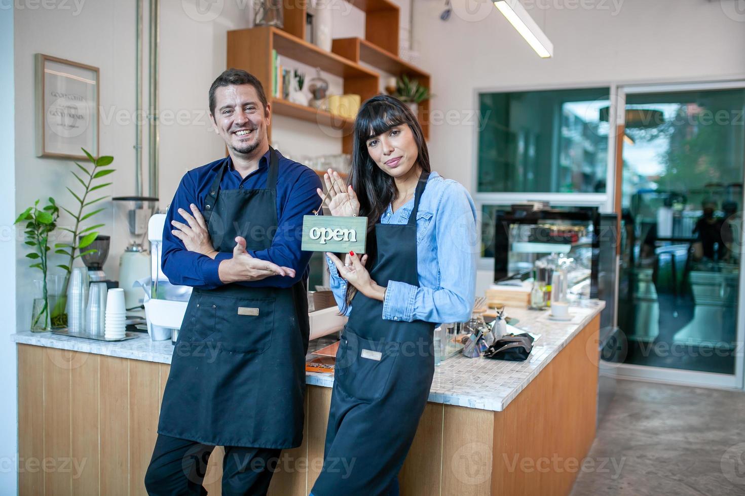 Portrait of smiling owner standing at his cafe. Coffee owner standing in front of coffee shop to welcome customer and open the coffee shop in morning. photo