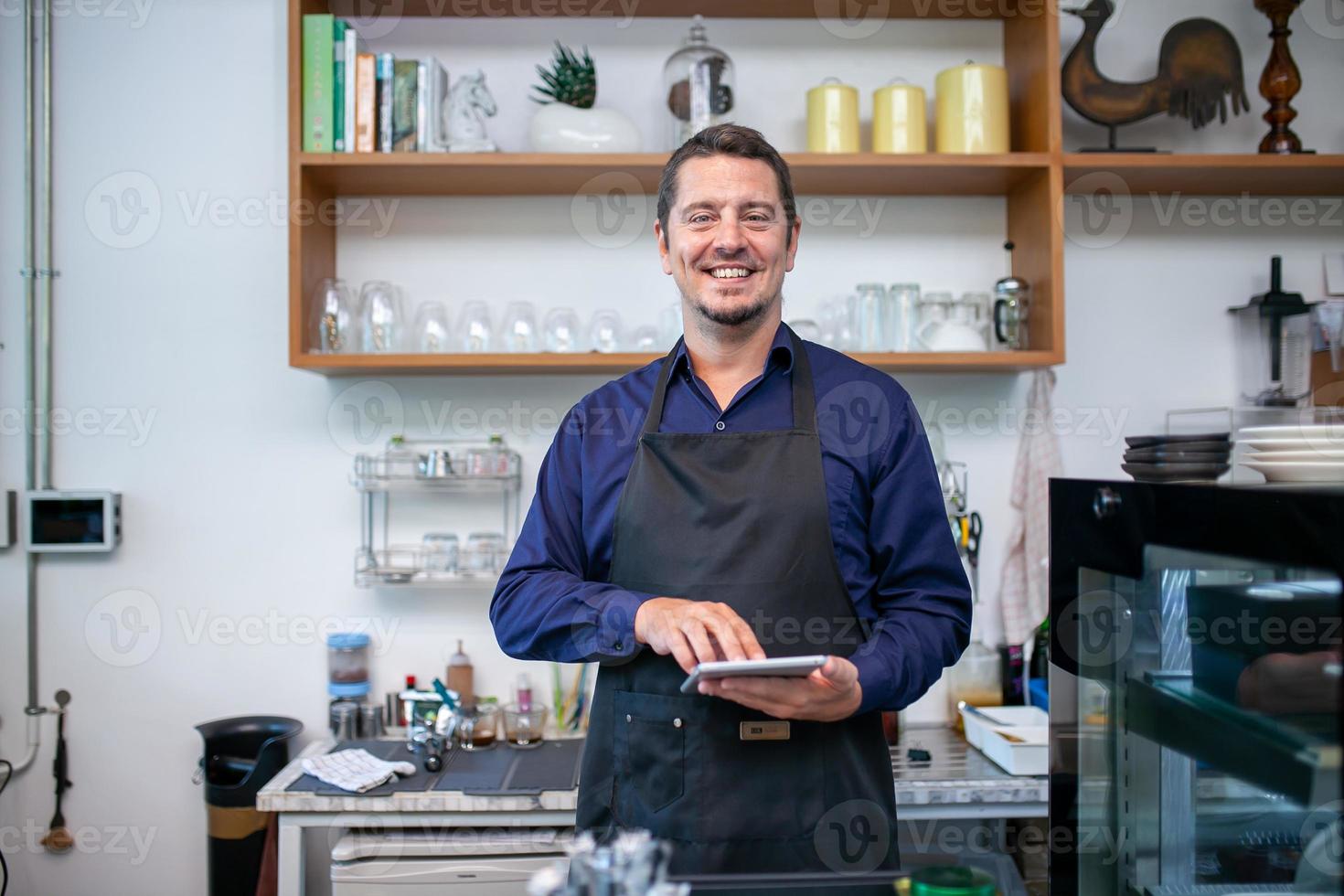 happy man barista using tablet for take order from customer in coffee shop. photo