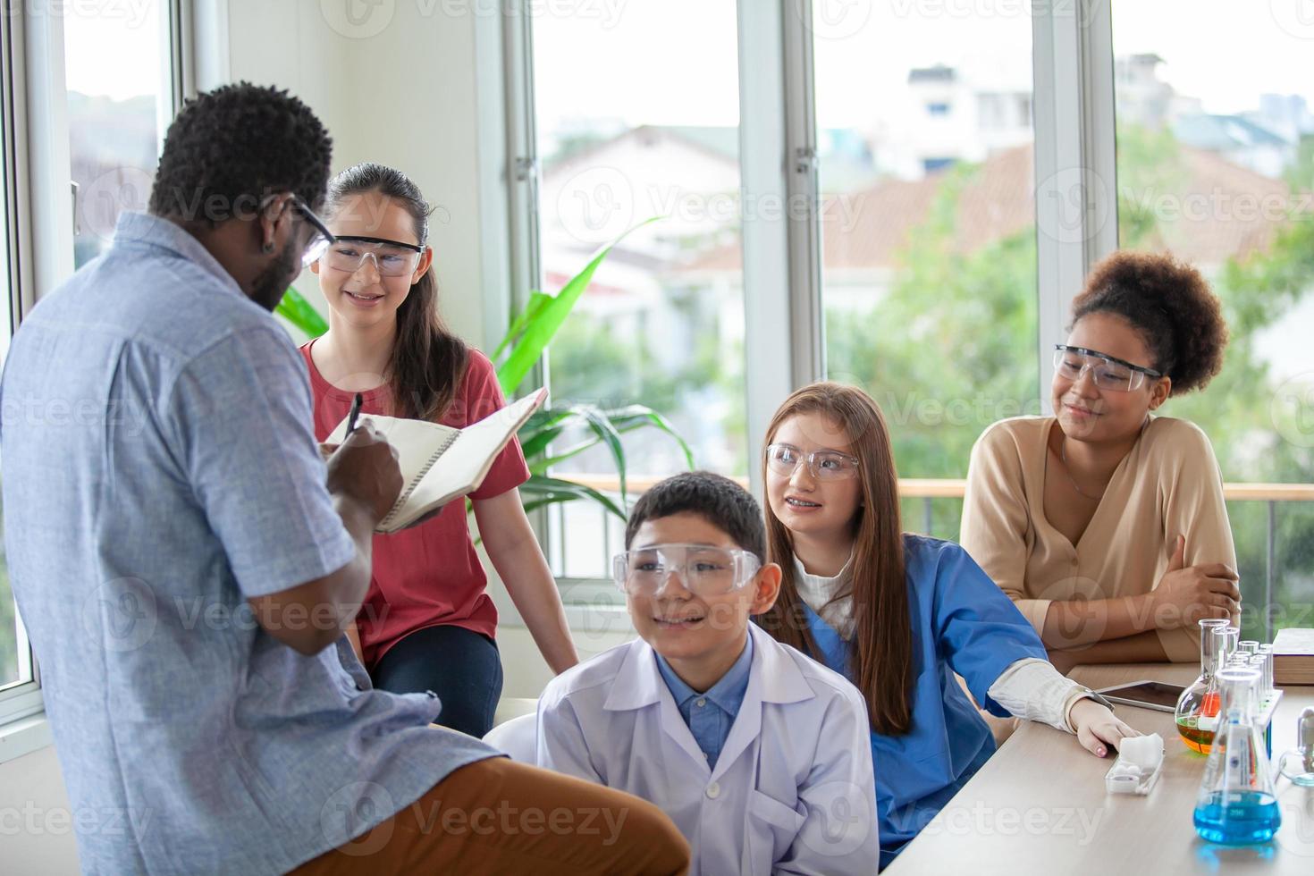 Students mixes chemicals in beakers. enthusiastic teacher explains chemistry to children, teacher teaching students in science class. photo