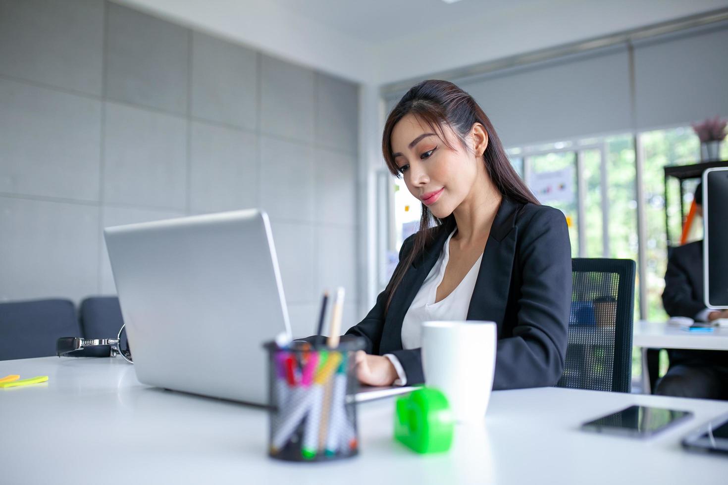 retrato de una hermosa mujer de negocios asiática que trabaja en la oficina, usando una computadora en la mesa. foto