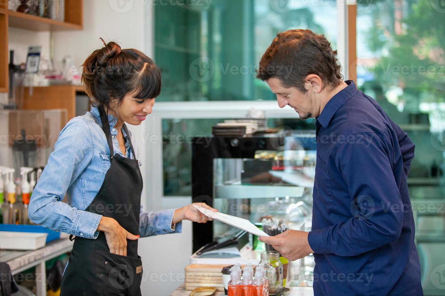 happy woman barista take order  from customer in coffee shop. photo