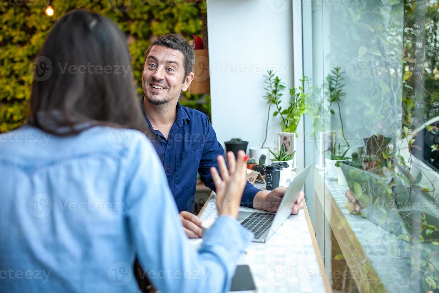 colegas hablando y usando portátiles trabajan juntos en la cafetería. foto