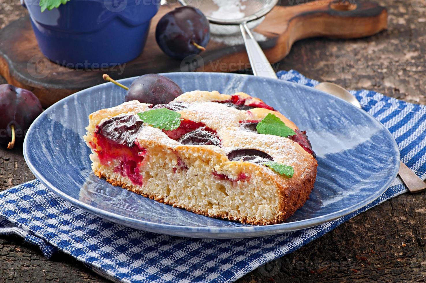 Delicious homemade cake with plums on a wooden background photo