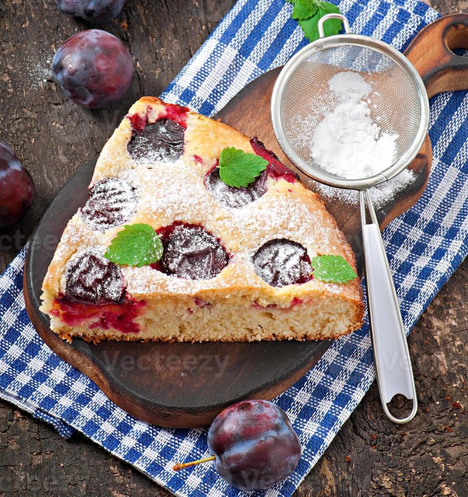 Delicious homemade cake with plums on a wooden background photo