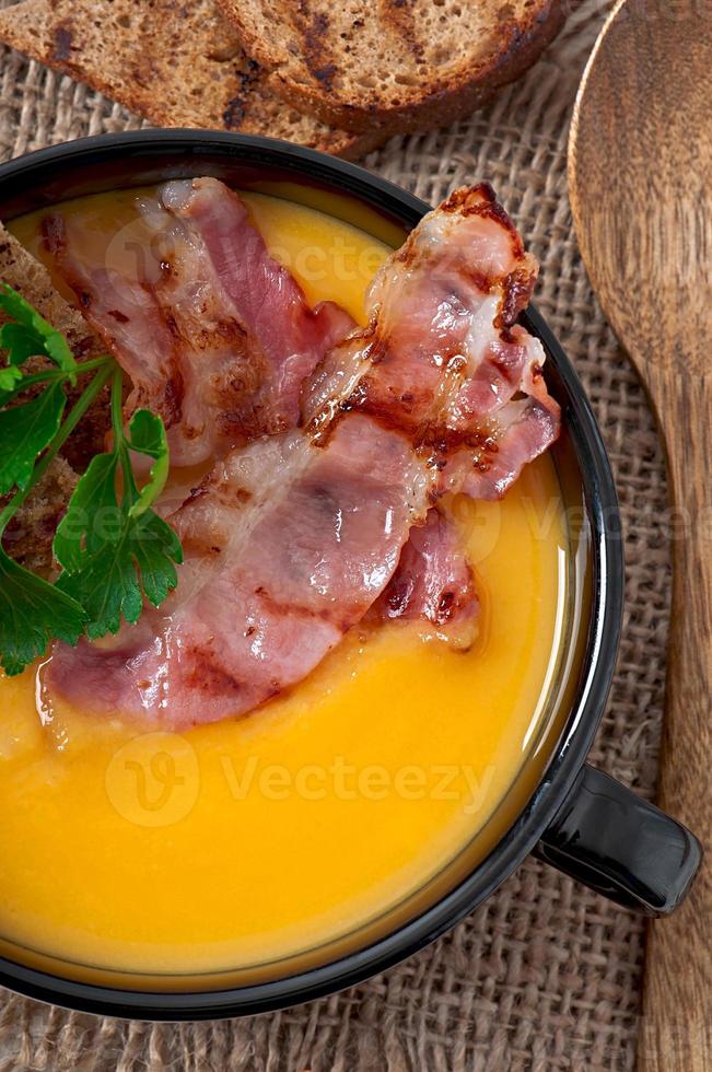 Cream of pumpkin soup with bacon and croutons photo