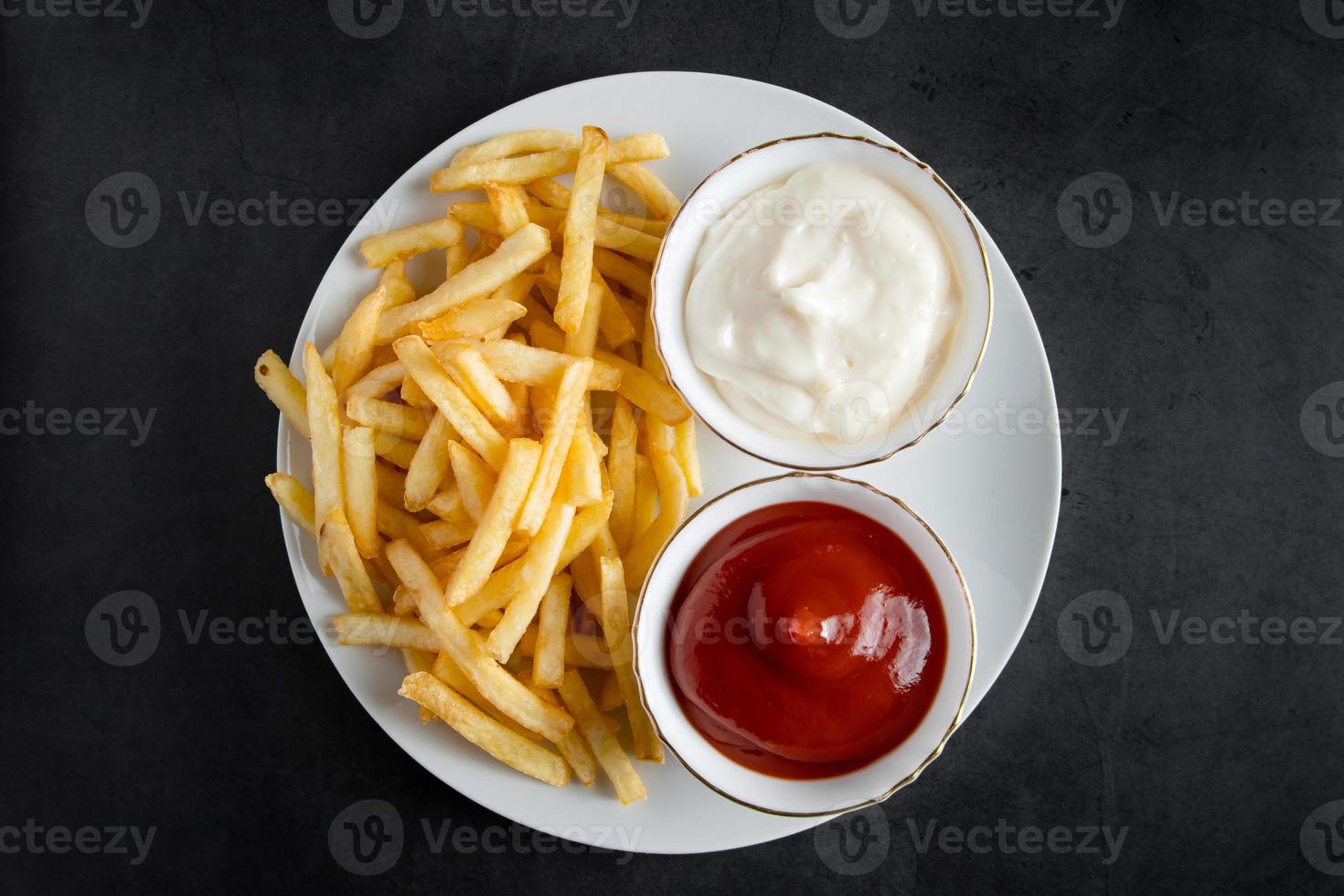 Appetizing crispy fries in plate on a black background. Hot american fast food. photo