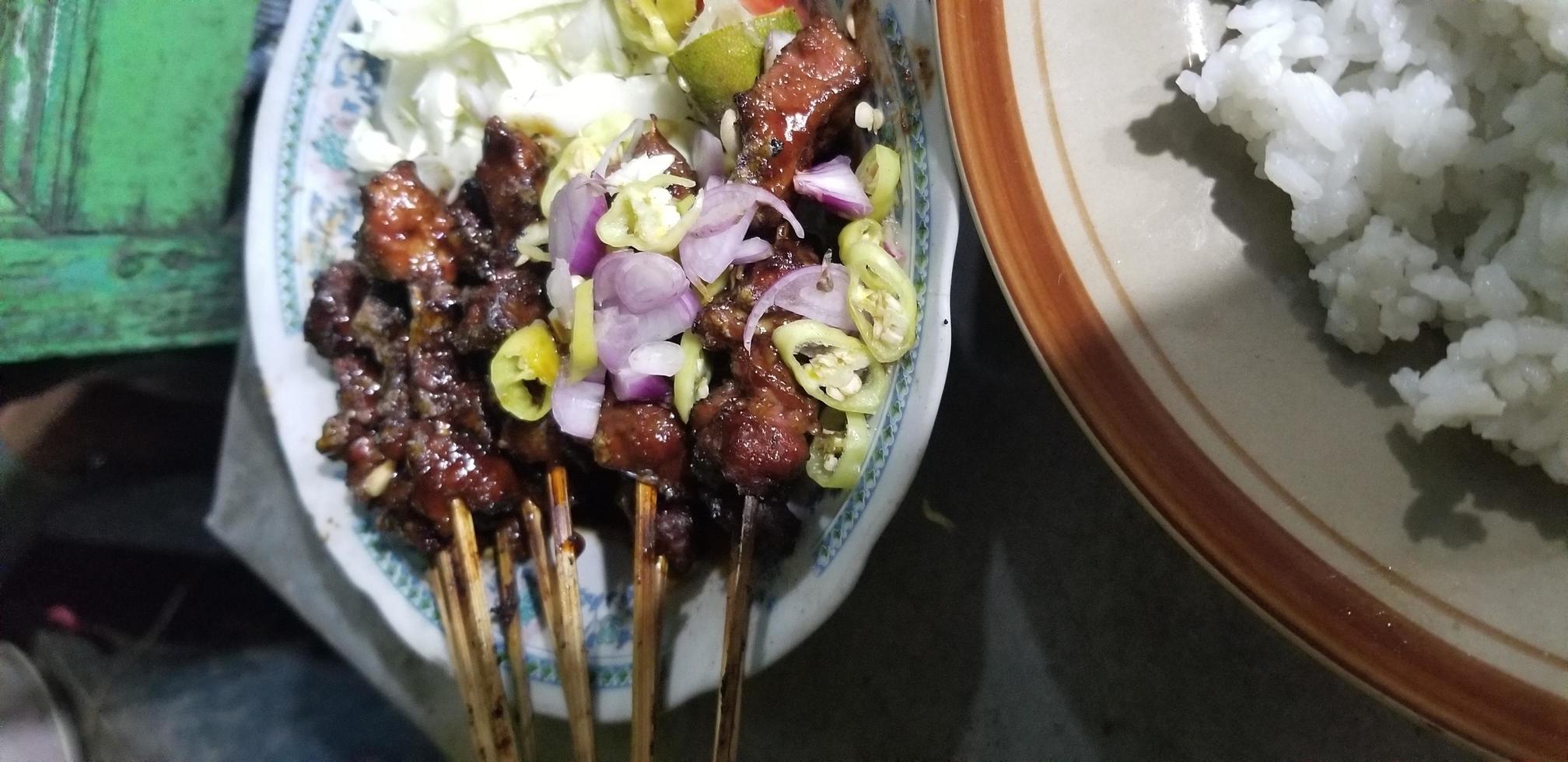 satay de cordero con especias y un plato de arroz foto