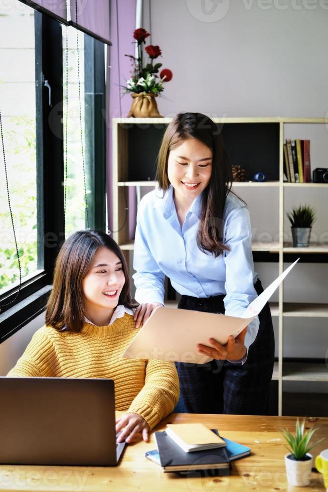 Two female company employees happily smiled at each other as they handed each other folders. photo