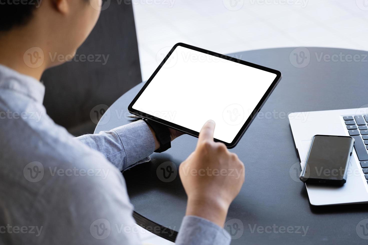 A man holding a tablet with a blank white screen. The blank space on the white screen can be used to write a message or place an image. photo