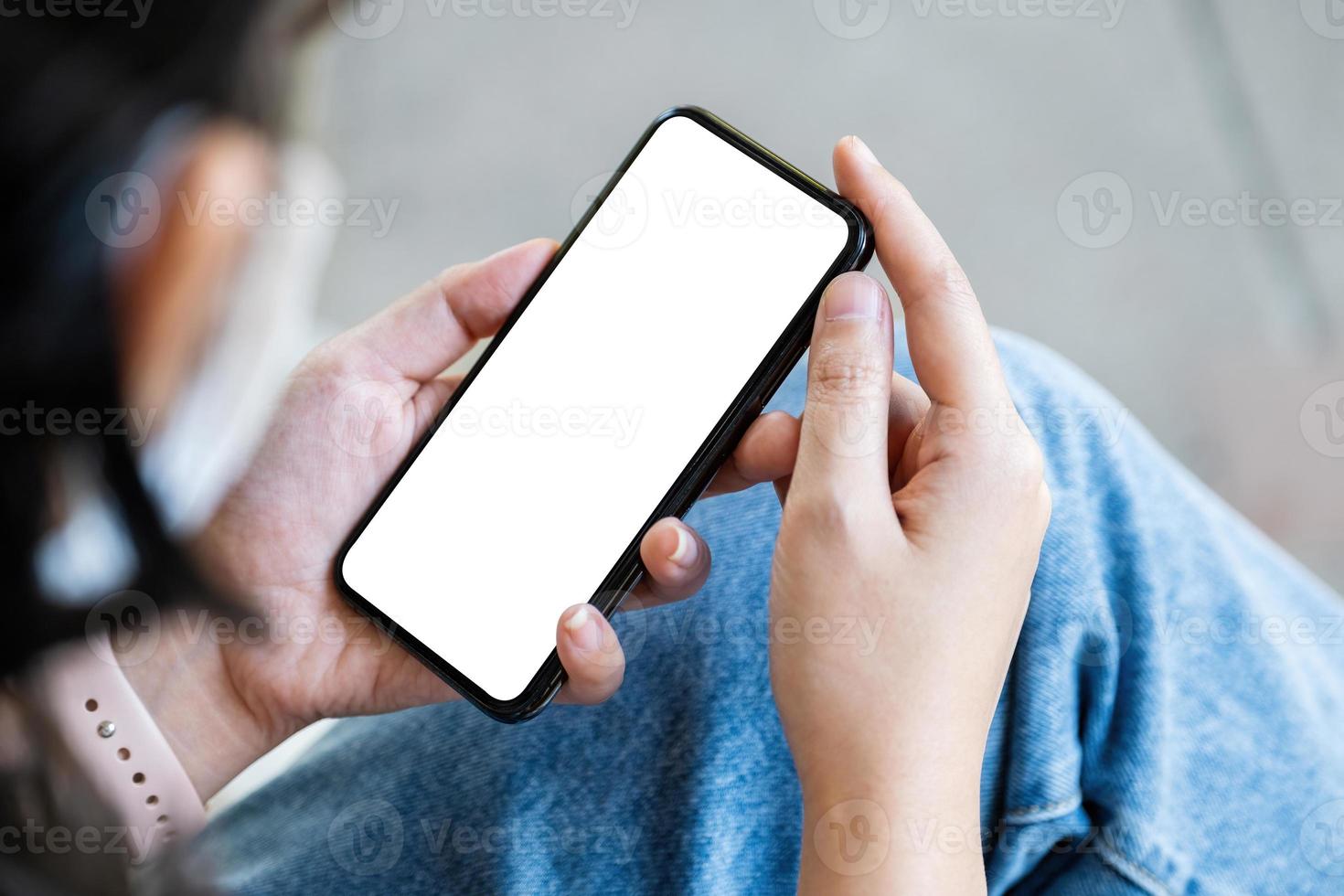 A woman holding a cell phone with a blank white screen. The blank space on the white screen can be used to write a message or place an image. photo