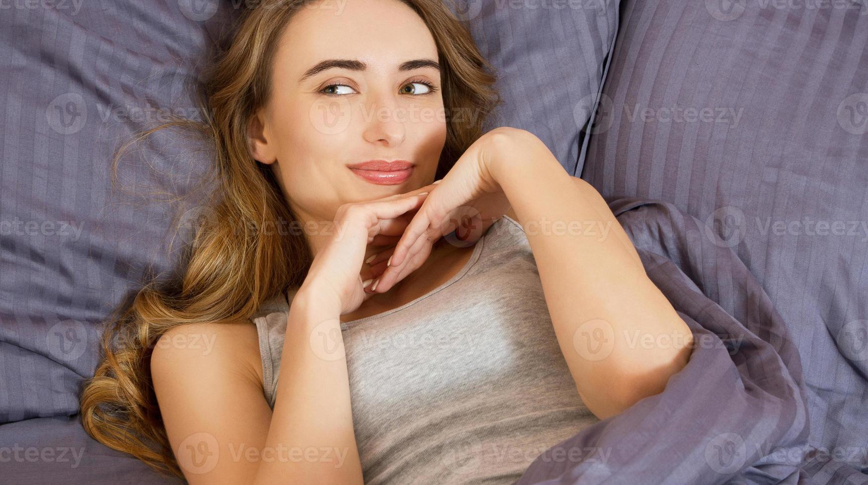 Pretty young beautiful woman on bed in modern apartment smiling after wake up photo