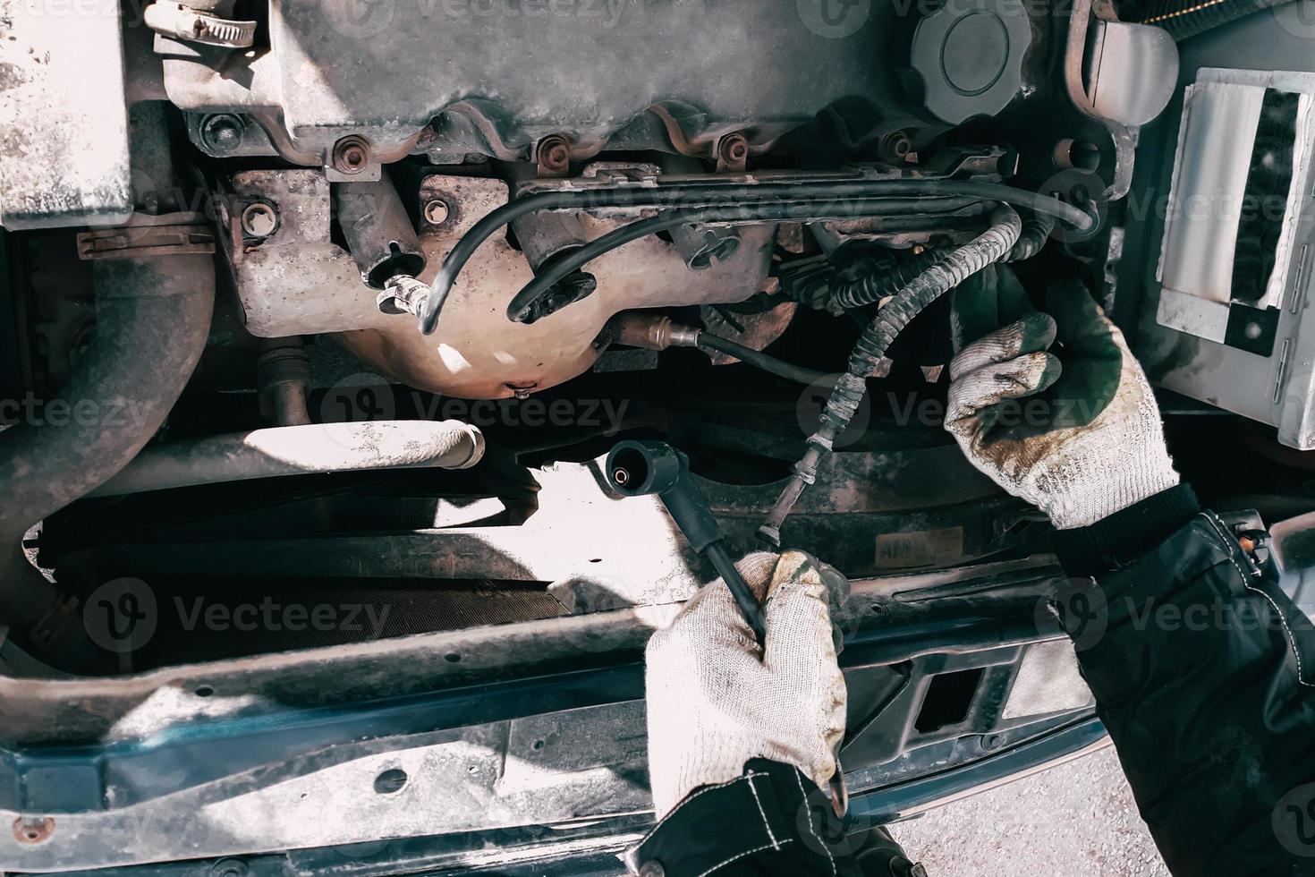 Replacing high-voltage wires on car engine. Man mechanic repairing an old vehicle is in service. Open hood auto photo